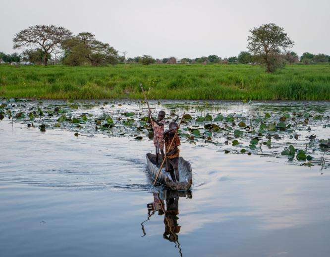 Children steering a canoe in Old Fangak
